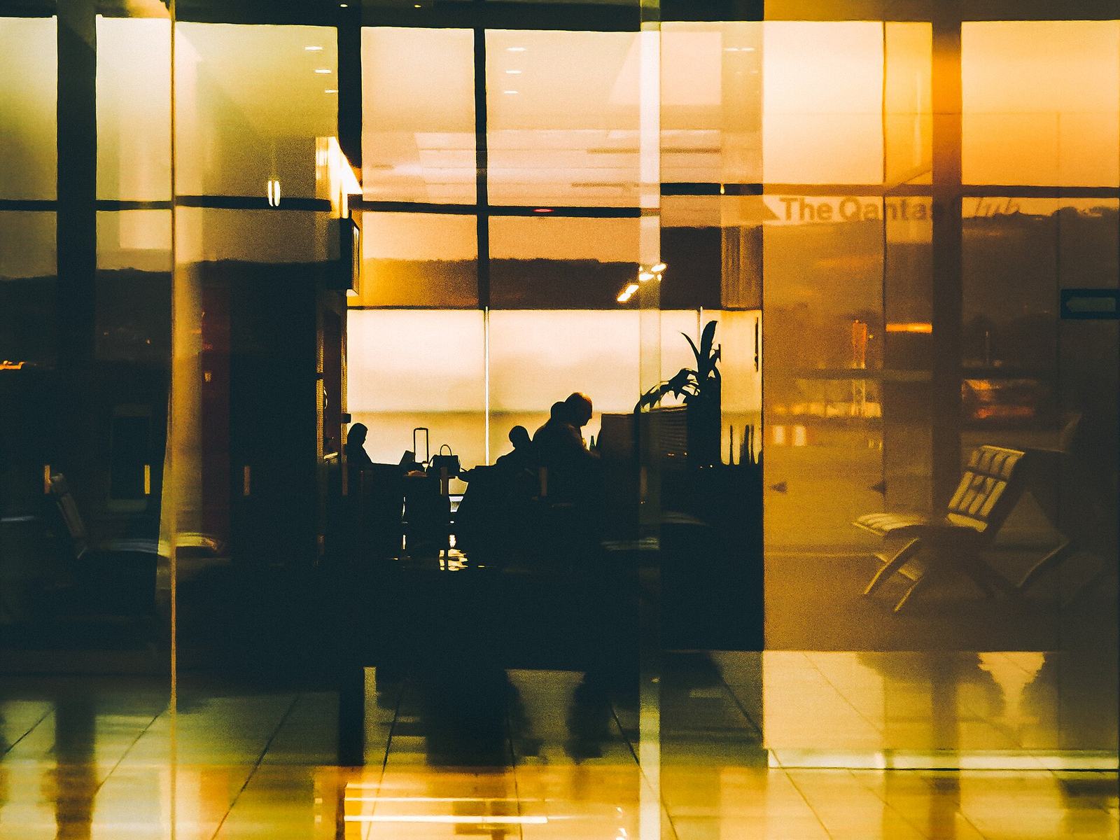 Travellers silhouetted against airport windows at sunset